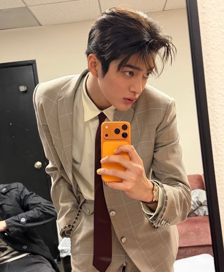 Jacob in a beige suit taking a mirror selfie